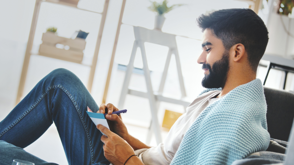 A man sitting in a chair writing a list
